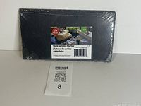 Front view of wrapped slate platter with product label showing size 23×13 cm