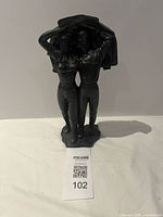 Front view of sculpture showing embracing couple with jacket overhead