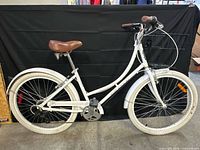 Full right-side view of white step-through cruiser bicycle with basket and fenders