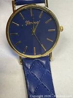 Front view of watch showing blue dial, gold-tone case and blue faux leather strap