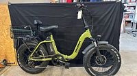 Full side view of green Taubik step-through e-bike with basket, battery, fat tires