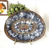 Front of oval enamel plate showing abstract blue, rust and white design