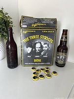 Group view showing McDonagh & Shea bottle, Three Stooges six-pack box, one labelled bottle and caps