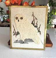 Front view of brass-framed snowy owl crewel embroidery