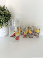 Pitcher and six tumblers grouped together showing fruit designs