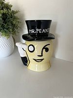 Front view of ceramic Mr. Peanut jar with top-hat lid and handle