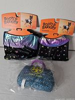 Two folded Boots & Barkley pet costumes with packaging and sealed Tory Bark plush toy