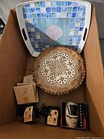 Box contents showing mosaic shell tray, carved wood plate, wood boxes, black horse figurines, ceramic houses, Trentino mug