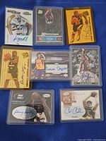 Seven sleeved autographed sports trading cards laid out