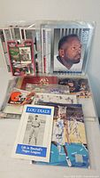 Group shot of all sports memorabilia including booklets, autographed photo, figure, card sets and helmet