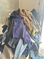 large pile of mixed denim and other pants on rack