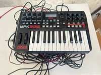 Front view of Akai MPK225 keyboard controller with keys, pads, wheels, cables visible