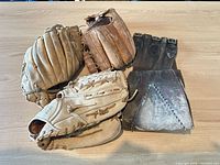 Three baseball gloves and protective guard laid out