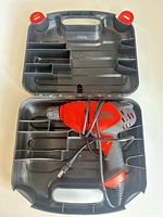 Black & Decker corded drill placed inside open molded plastic carry case showing interior compartments and attached power cord