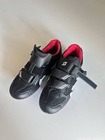 Top view of pair of Peloton cycling shoes showing straps, red interior and brand logo