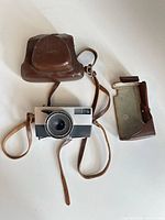 Camera with both pieces of leather case and strap visible