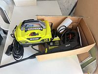 Pressure washer in carton with cord and spray gun visible