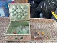 Open wicker sewing basket, plastic tray with threads and bobbins visible
