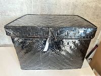 Full view of glossy black woven basket with lid closed