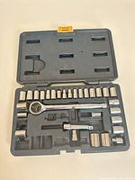 Open plastic case showing ratchet, extension, adapters and multiple sockets