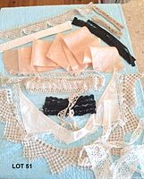 Entire lot spread out on blue quilt showing bralette, collars, sash, garters