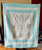 Full view of quilt showing turquoise border and embroidered centre