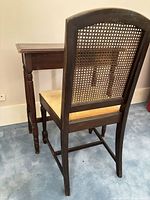 Rear view of caned back chair positioned at small wooden table