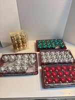 Overview of all packaged ornament sets in silver, red, green and gold