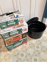 Stacked boxed sets of Bernardin mason jars beside enamel canning pot