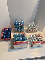 Five boxes/tray of blue and silver ball ornaments on table