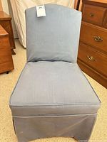 Front view of light blue slipcovered armless accent chair showing overall design and condition