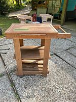 Front view of wooden kitchen cart showing top, shelves, towel bar and casters