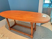 Overall view of oval coffee table on carpet, showing top, legs, stretcher