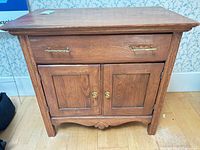 Front view of solid wood cabinet showing drawer, double doors, hardware and overall finish