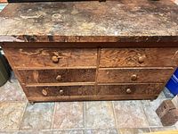 Front view showing six drawers, paint-stained top, wood grain and wear