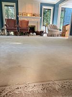 Wide view of off-white rug covering room floor with fringe foreground