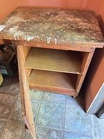 Front view of cabinet showing door, shelf, casters, paint-splattered top