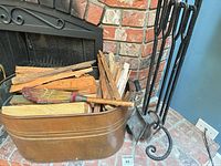 Tools on stand beside brick fireplace with bucket of kindling