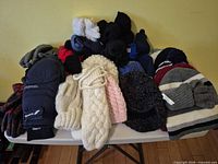 Assorted hats, mittens and gloves arranged on table