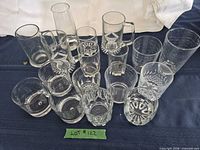 Group shot of all 15 clear glasses arranged on blue cloth