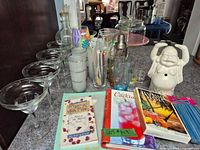 Overall lot showing margarita glasses, highball glasses, shaker, stirrers, Buddha jar, books