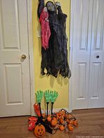 Full lot view: grim reaper hanging, stakes, lights, mask, pumpkin