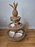 Full view of tiered carved wood stand with shell bowls and utensils