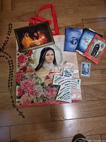 Entire lot laid out: rosary, framed print, tote, plaque, books, prayer card