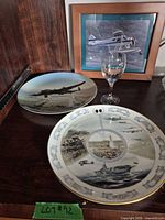 Overall lot showing two plates, wine glass and framed aircraft print