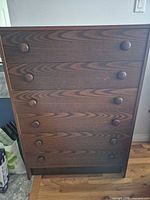 Front view of tall six-drawer dresser showing wood grain veneer and round knobs