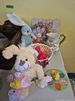 Group shot showing plush bunnies, ceramic basket with eggs, pitcher, egg plate and wreath