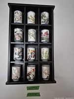 Front view of nine porcelain floral cups in display rack