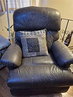 Front view of gray leather recliner with pillow