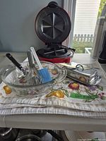 All items grouped: sandwich maker open, casserole, butter dish, whisk, spatula, knife